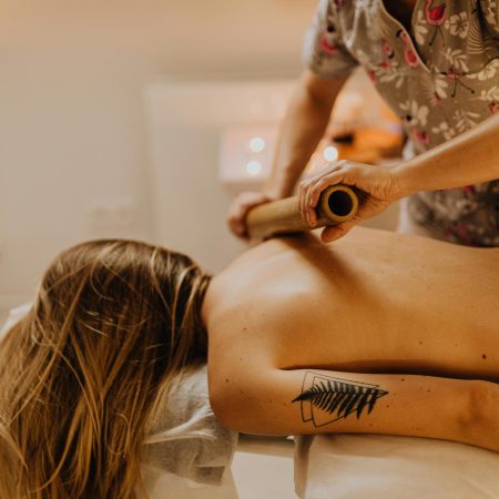 A serene spa experience with a massage therapist working on a woman's back using bamboo sticks.